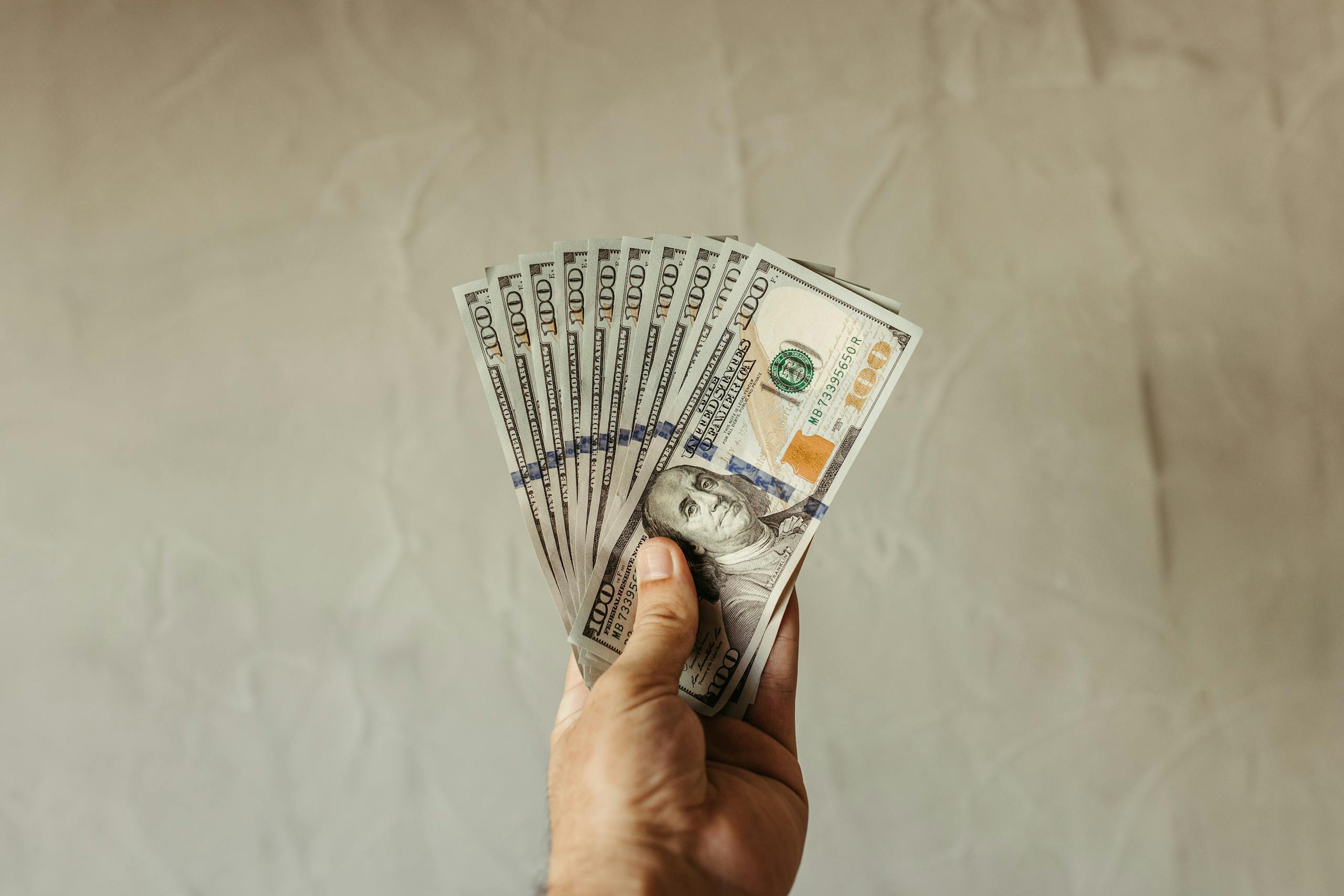A close-up of a hand holding multiple US dollar bills, showcasing wealth and finance concepts.